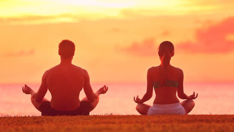 Meditation yoga couple meditating at serene beach sunset. Girl a